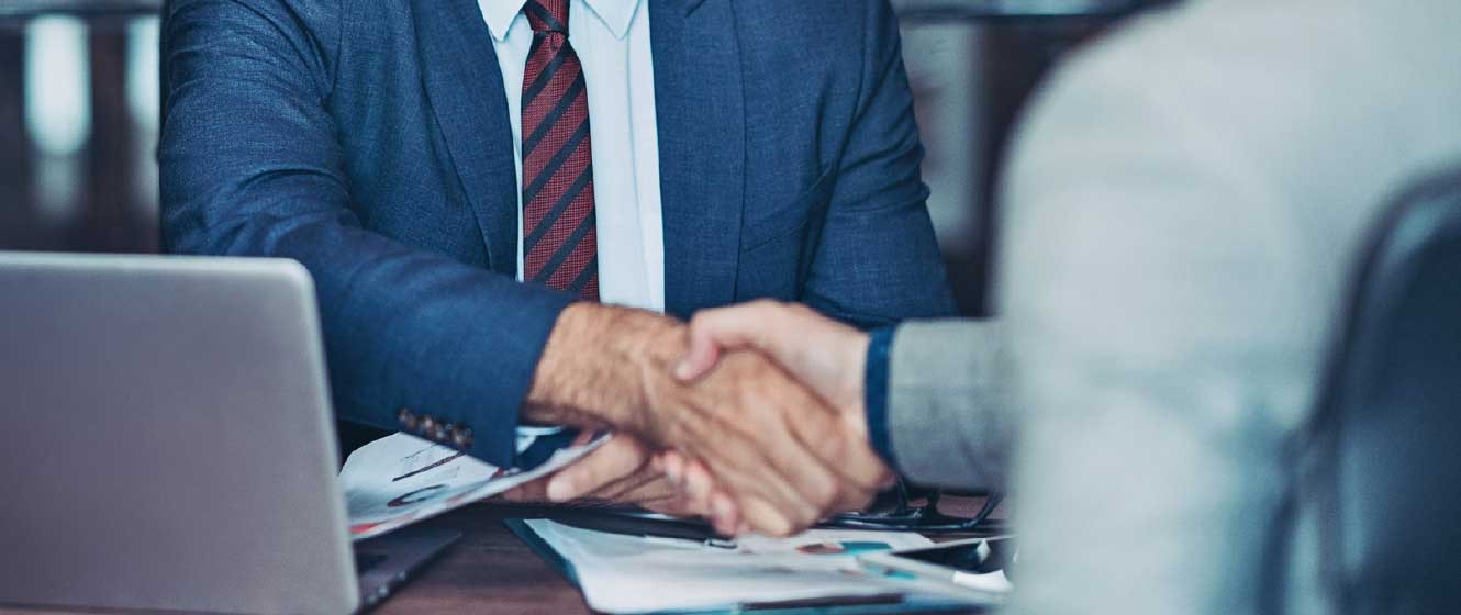 Close up of two people shaking hands over a desk