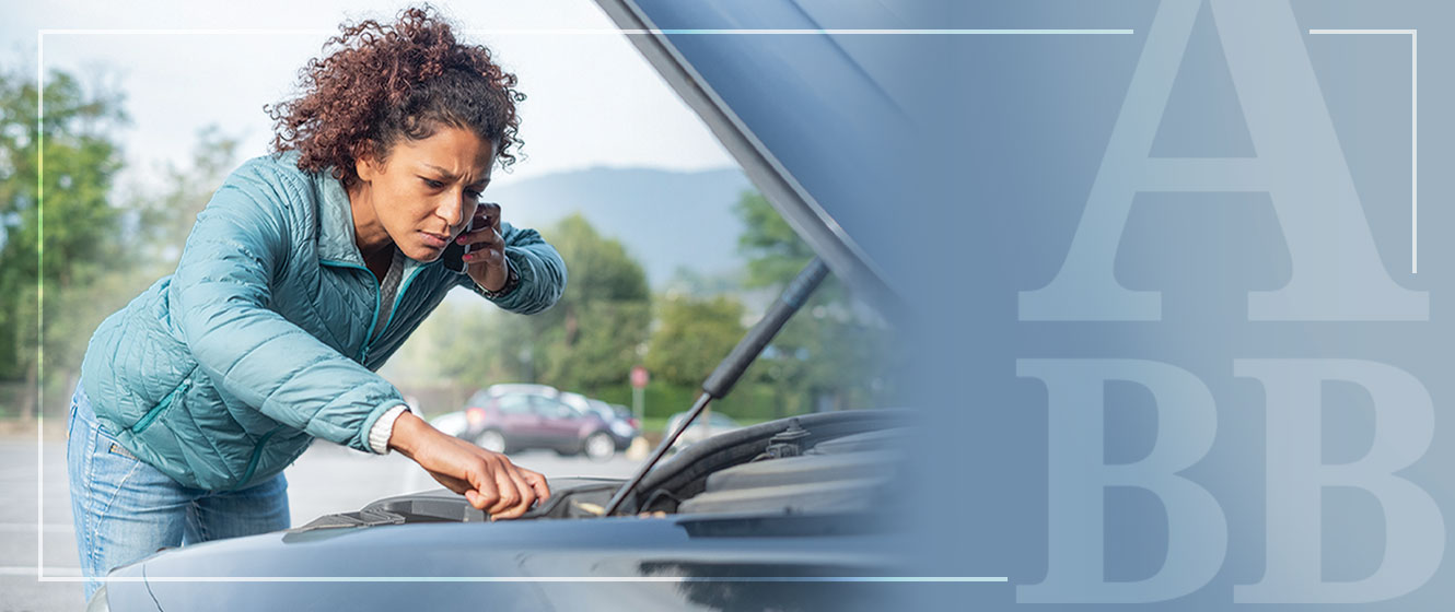 Woman on phone and looking under car hood